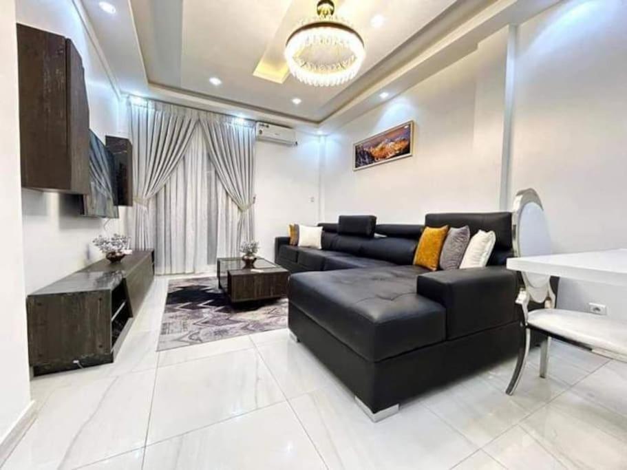 ein Wohnzimmer mit einem schwarzen Sofa und einem TV in der Unterkunft Spacieux duplex à louer à Dakar in Dakar