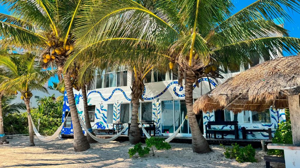 a building on the beach with two palm trees at Pronoia Casa de Playa in Mahahual