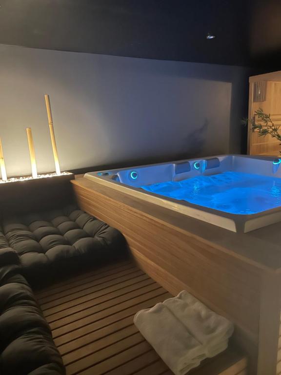 - une grande baignoire bleue dans une chambre avec un canapé dans l'établissement Linfinity, à Baillonville