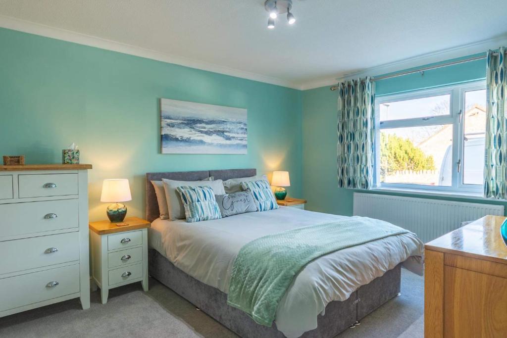 a bedroom with a bed with blue walls and a window at The Portwey Pearl in Rodwell