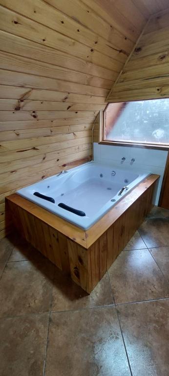 eine große Badewanne in einem Holzzimmer mit Fenster in der Unterkunft Chale com hidromassagem da Vick in Campos do Jordão
