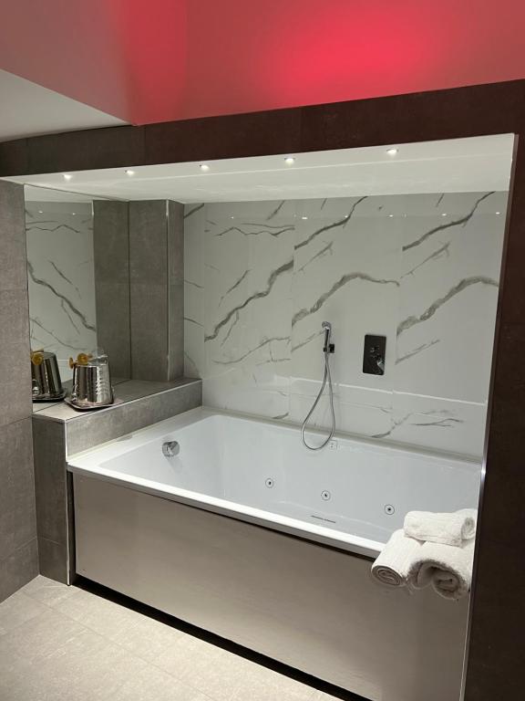 a bath tub in a bathroom with a marble wall at LEMON SUITES APARTMENTS in Rome