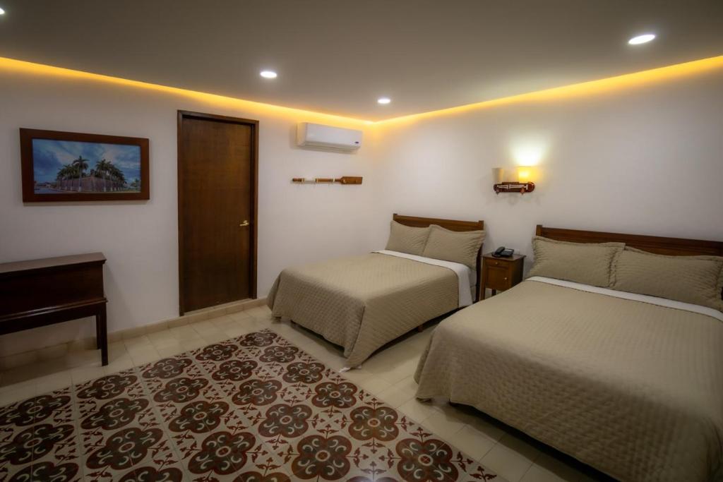 a bedroom with two beds and a desk and a rug at El Navegante in Campeche