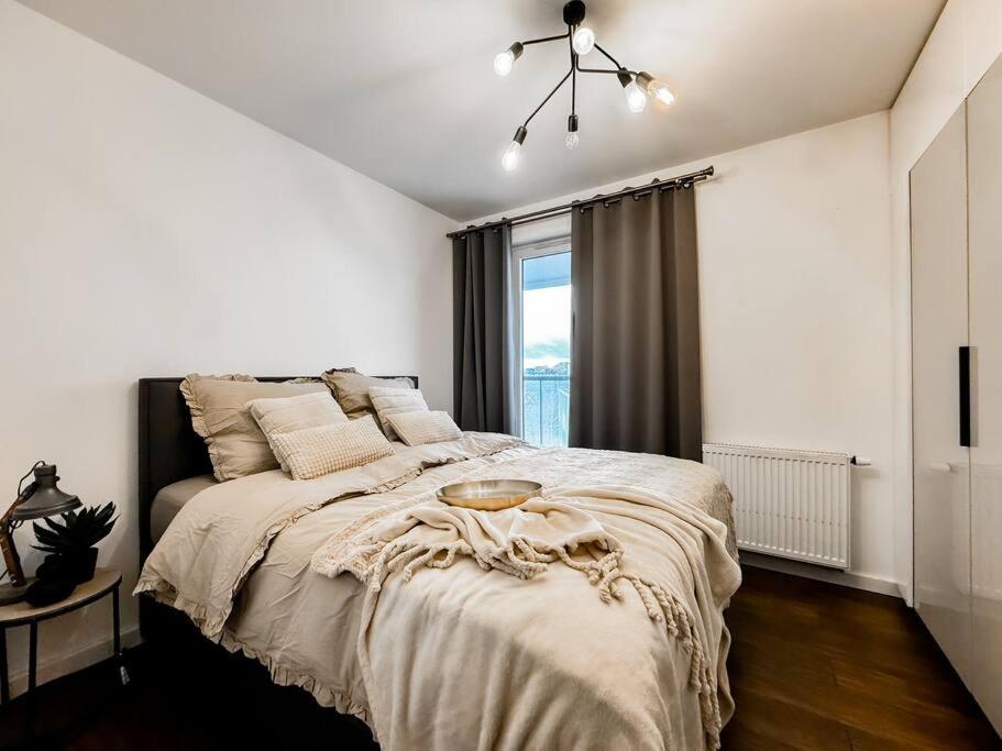 a white bedroom with a large bed and a window at Apartament 101 Kępa Mieszczańska in Wrocław