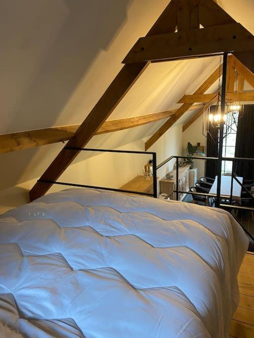 a white bed in a room with an attic at Gastenverblijf A&amp;A met mezzanine in Gavere