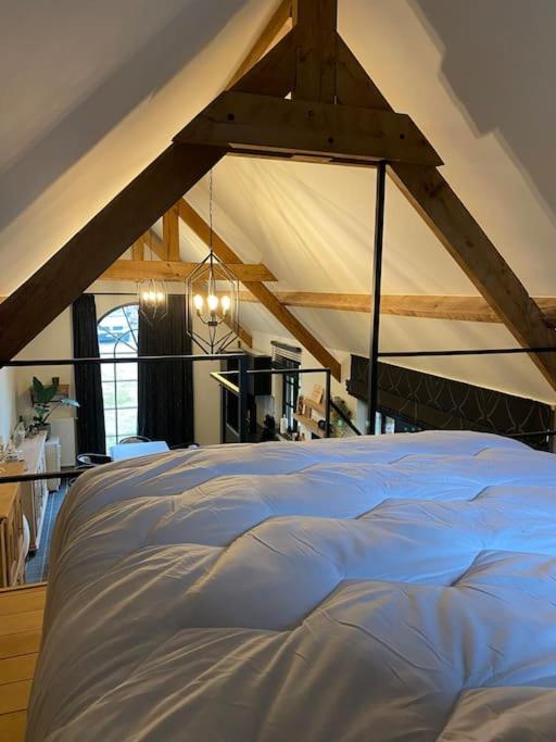 a bedroom with a large white bed in a attic at Gastenverblijf A&amp;A met mezzanine in Gavere
