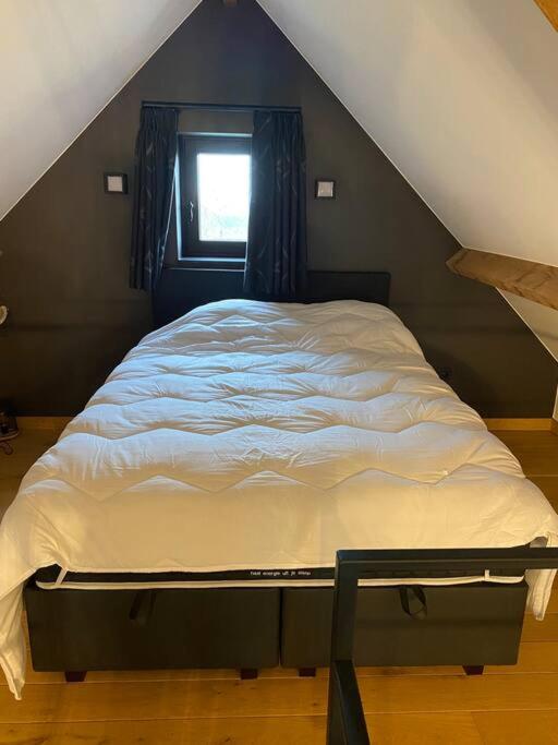 a large bed in a attic with a window at Gastenverblijf A&amp;A met mezzanine in Gavere
