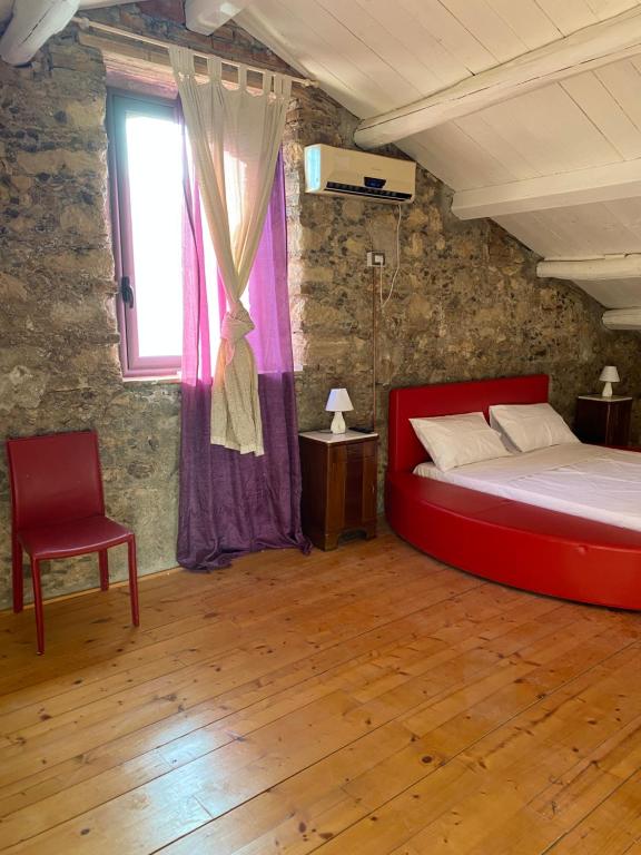 Marano MarchesatoにあるIl Casaleのベッドルーム(赤いベッド1台、椅子付)