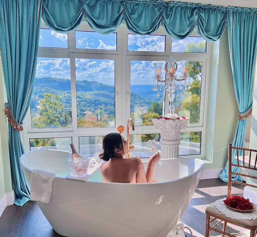 Le Boutique Hotel Gramado - Exclusivo para Casais في غرامادو: امرأة تجلس في حوض الاستحمام أمام النافذة