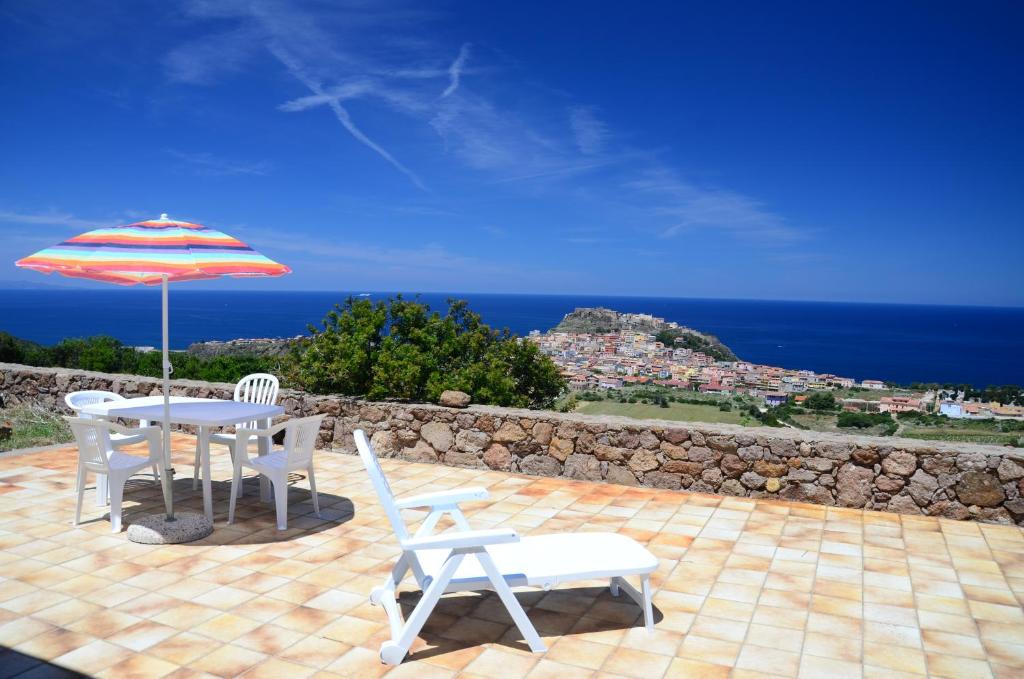Un patio con una mesa y sillas y una sombrilla. en Villetta Muntelgu, en Castelsardo