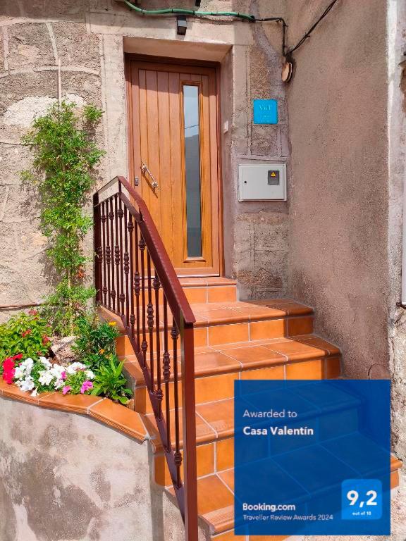 a house with a wooden door and stairs with flowers at Casa Valentín in Casillas