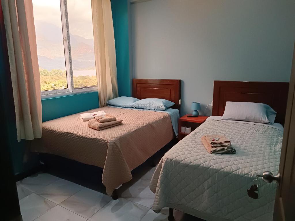 two beds in a room with a window at Casa Chikuwa in San Juan La Laguna