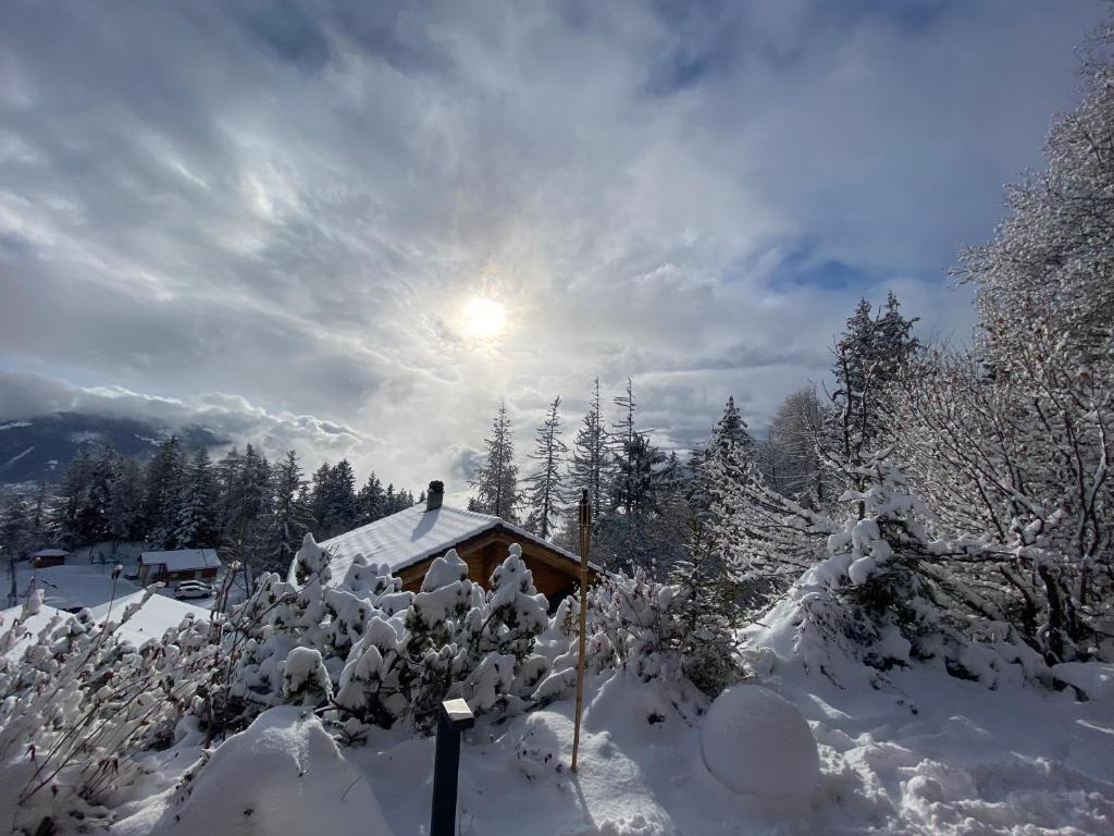 eine schneebedeckte Hütte mit der Sonne am Himmel in der Unterkunft Superbe chalet 12 personnes vue imprenable 2nuits min in Anzère