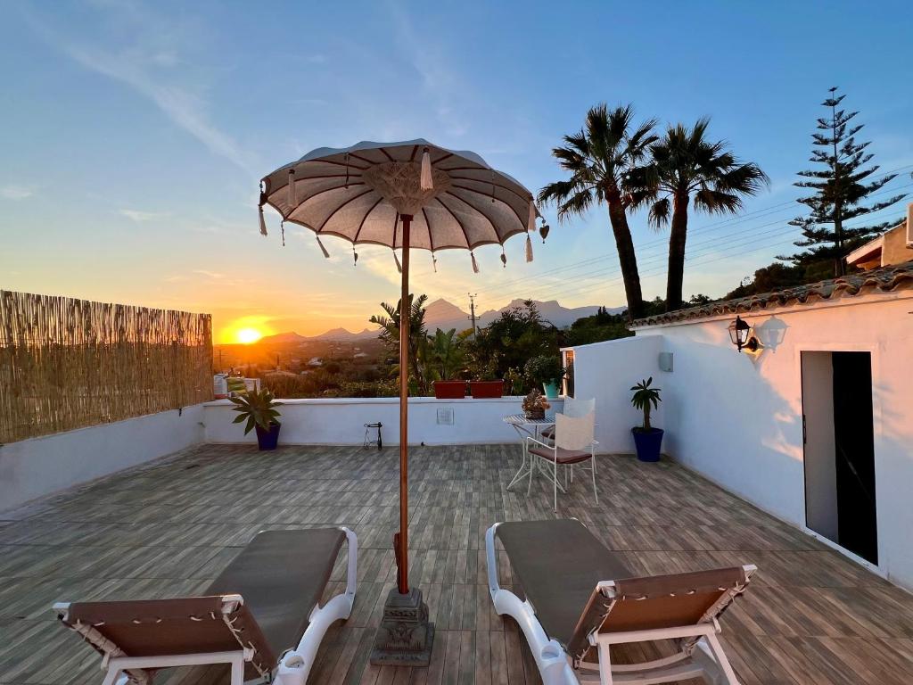 a patio with an umbrella and chairs and the sunset at Hotel Altea Paradise 1917 - Adults Only in Altea