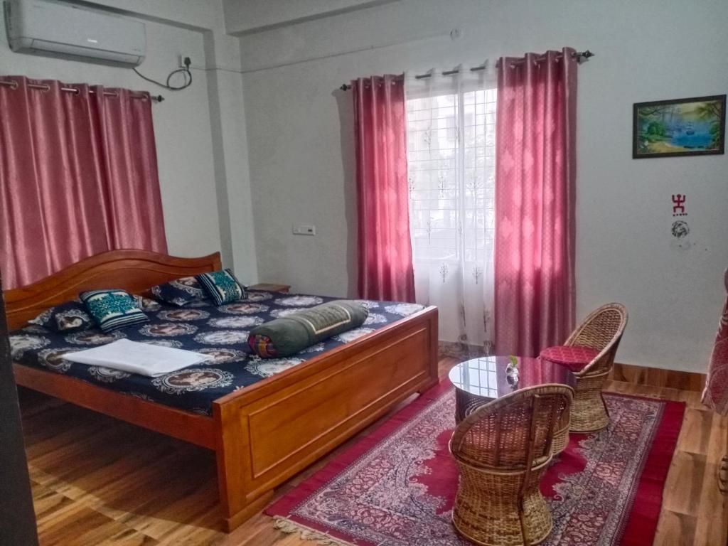 a bedroom with a bed and two chairs and a table at Areca Holiday Apartment in Siliguri