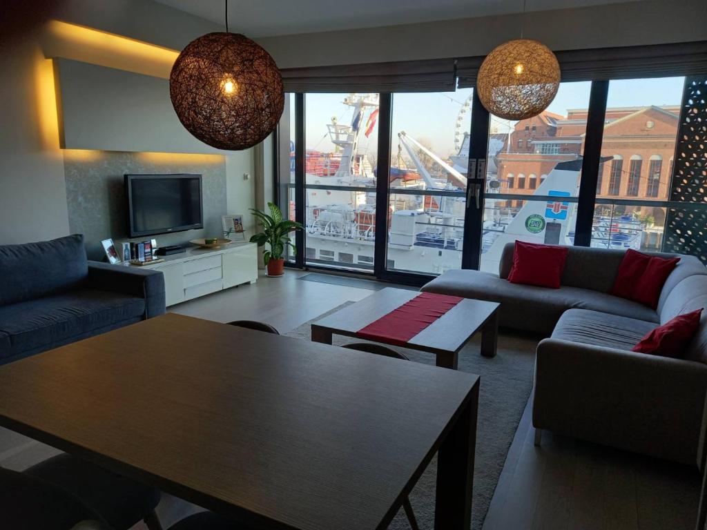 a living room with couches and a table and a tv at Apartment with an Amazing View in Gdańsk