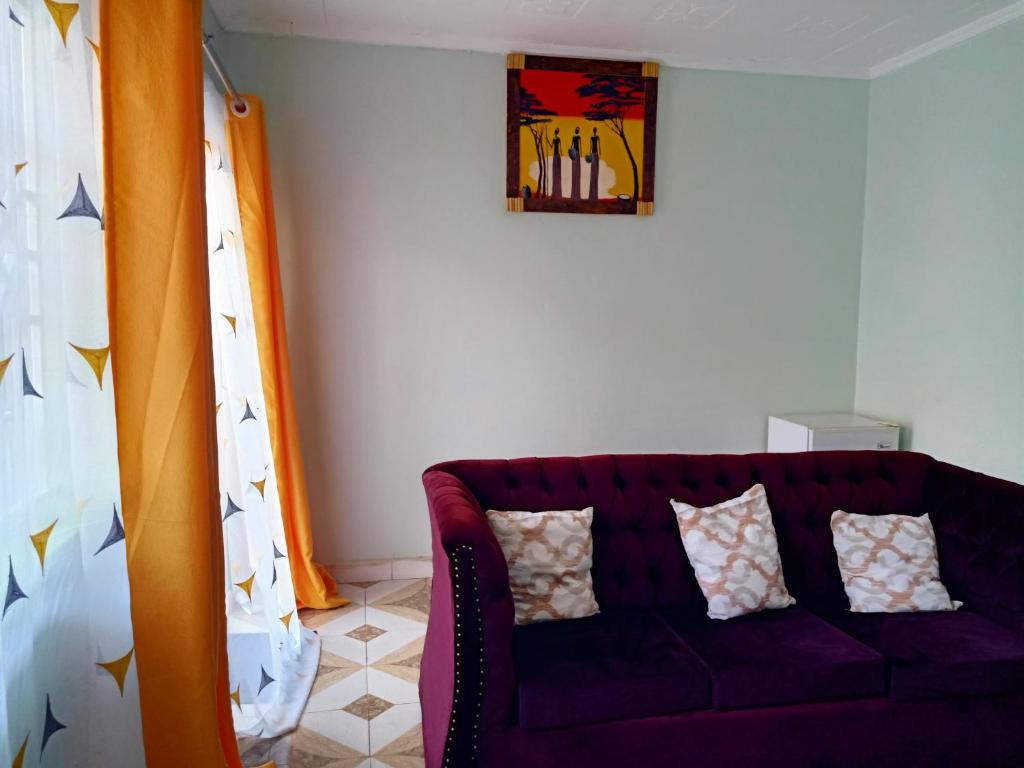 un salon avec un canapé violet et un tableau dans l'établissement Nash Apartment Ekero, à Mumias