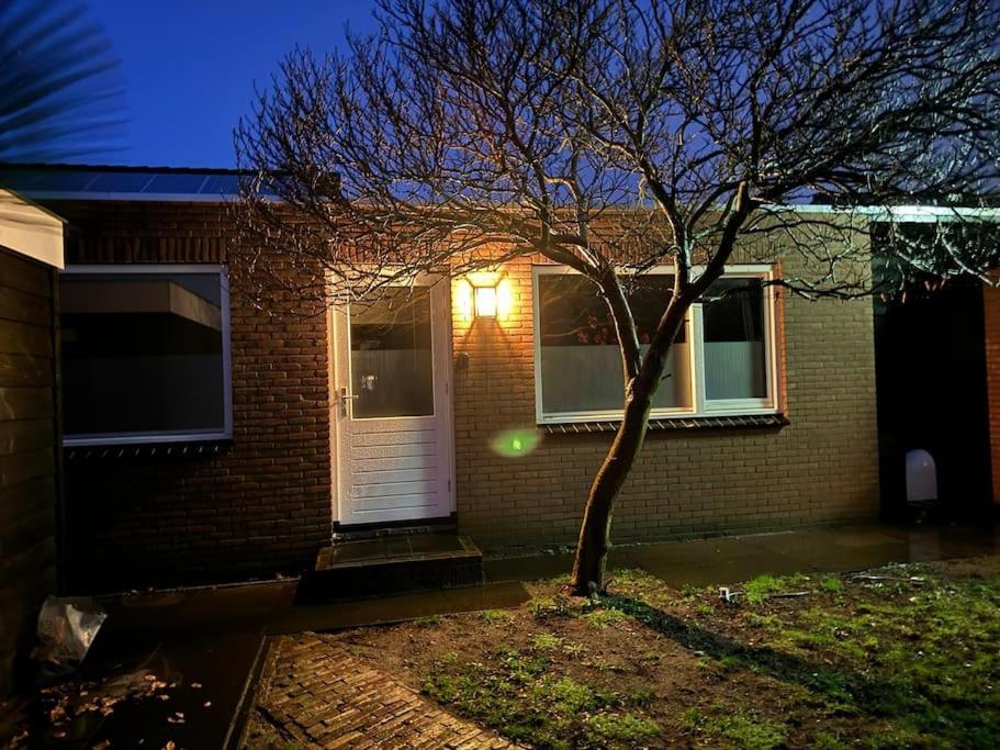 een huis met een boom en een witte deur bij Luxe woning Bubbles! Met airco en Parkeren op eigen grond in Castricum