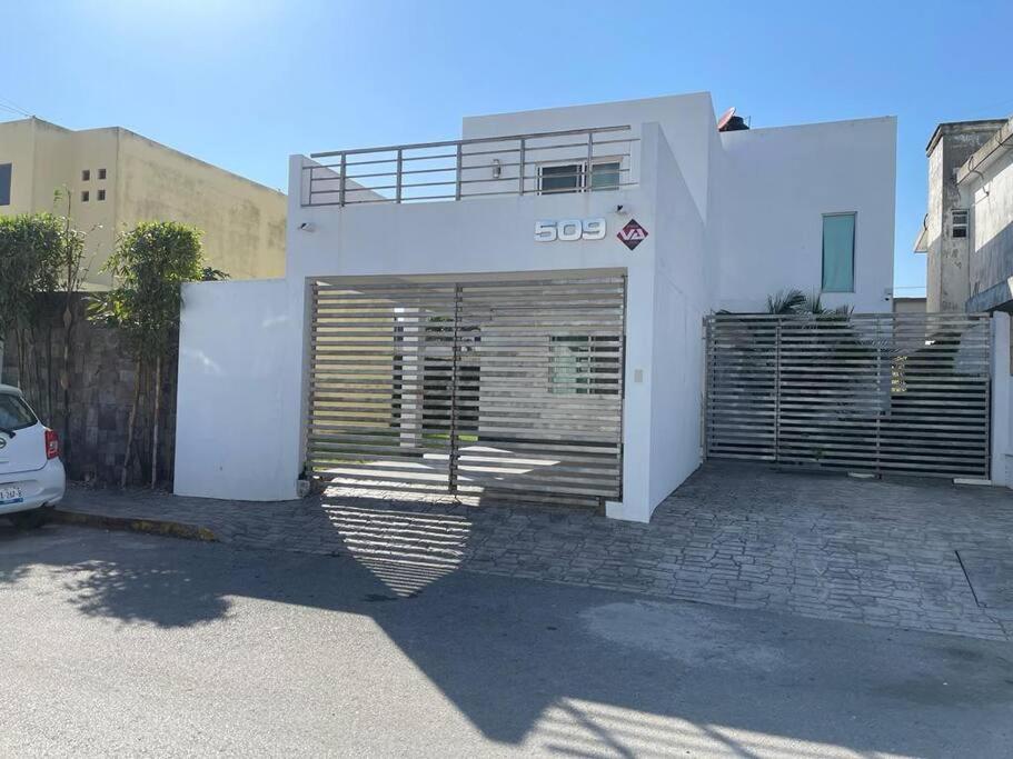 ein weißes Haus mit einem Tor auf einem Parkplatz in der Unterkunft Casa confortable cerca de playa in Ciudad Madero