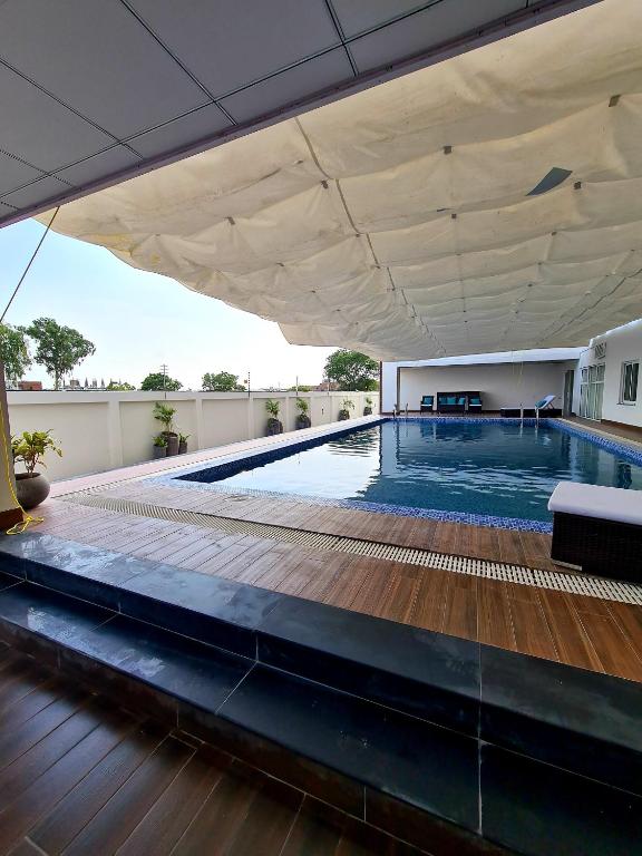 a large swimming pool with a wooden floor and a white ceiling at 1 Bed Modern Apartment, Pool, Gym, Cinema in Lahore
