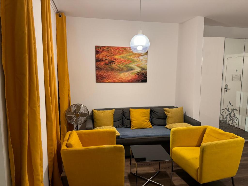a living room with a couch and two yellow chairs at GREENY in Wrocław