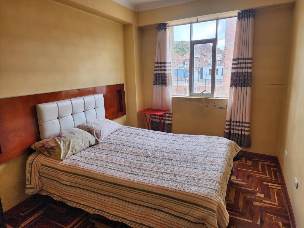 a bedroom with a large bed with a window at HOSPEDAJE FESTEJOS in Juliaca