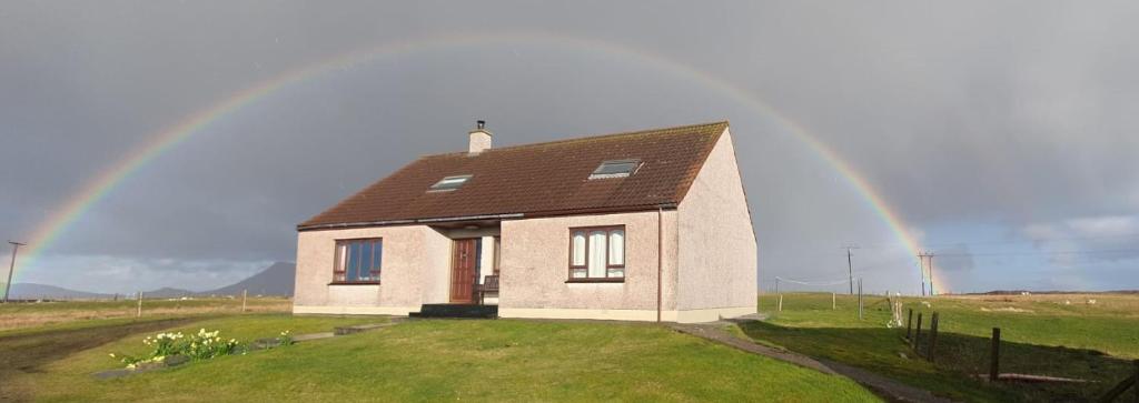 a house with a rainbow in the sky at Taigh Mairi Grimsay in Carinish