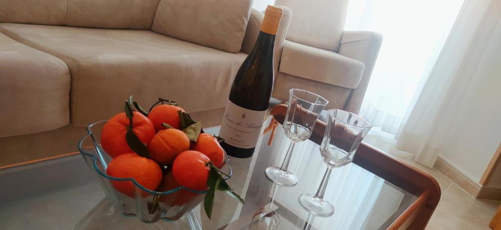uma mesa de vidro com um cesto de laranjas e garrafas de vinho em La Linea em Calpe