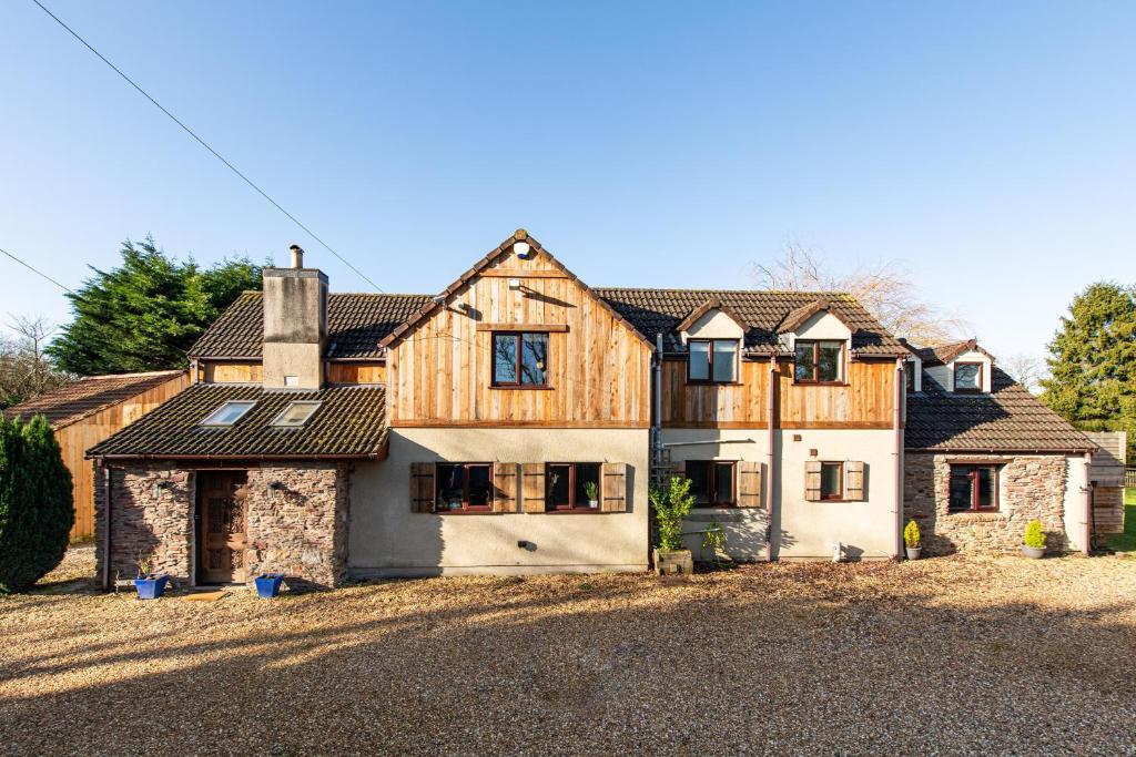 a large house with a stone and wood at Cheerful 7-bedroom house with hot tub sleeps 24 in Iron Acton