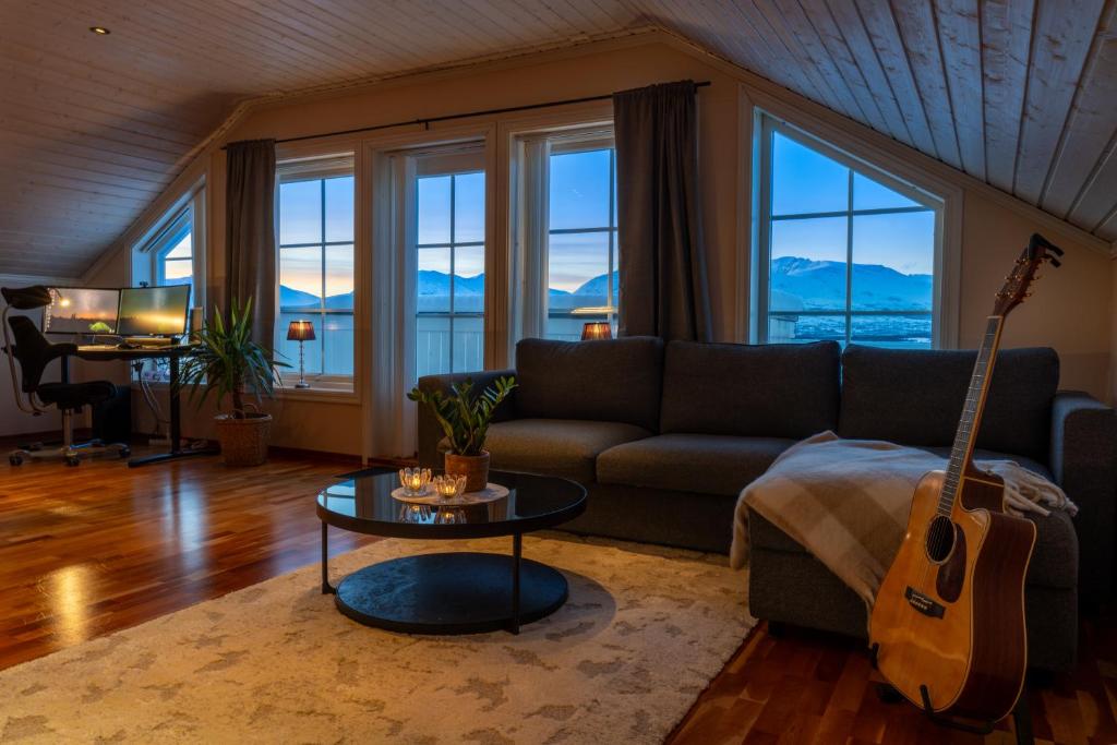 a living room with a couch and a guitar at Panoramic Penthouse in Trondalen