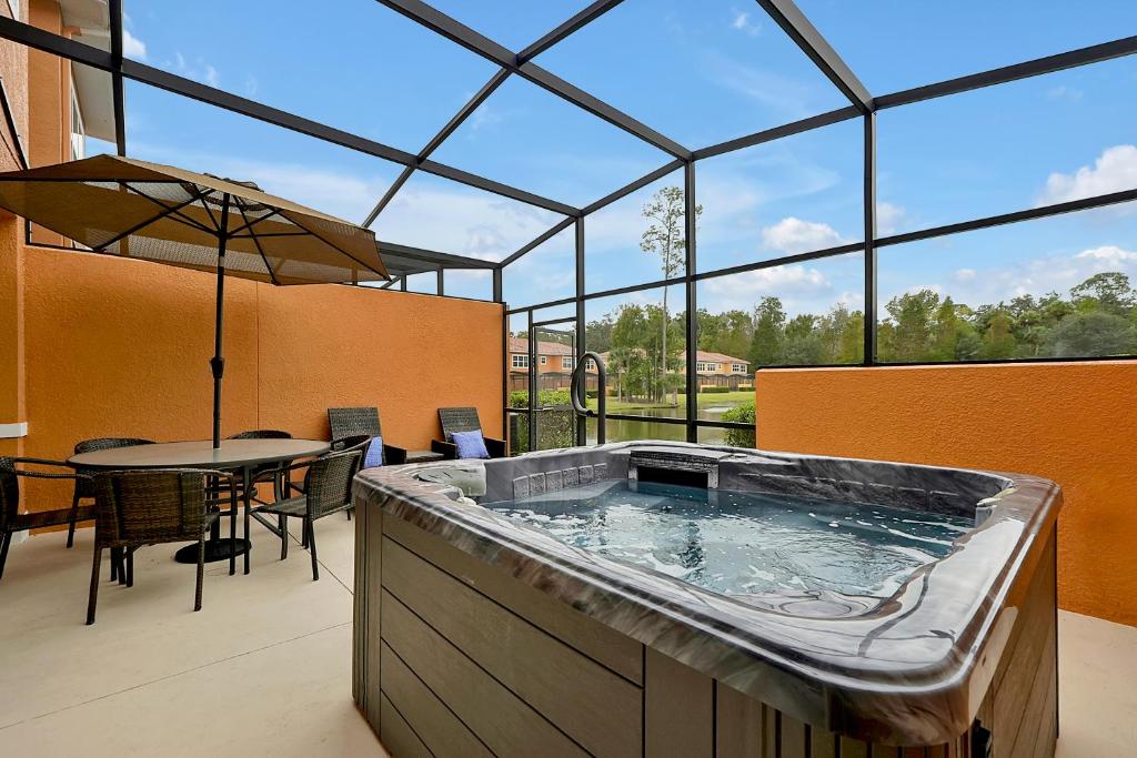 Regal Oaks Resort Vacation Townhomes by IDILIQ في أورلاندو: حوض استحمام ساخن كبير في مبنى مع طاولة وكراسي