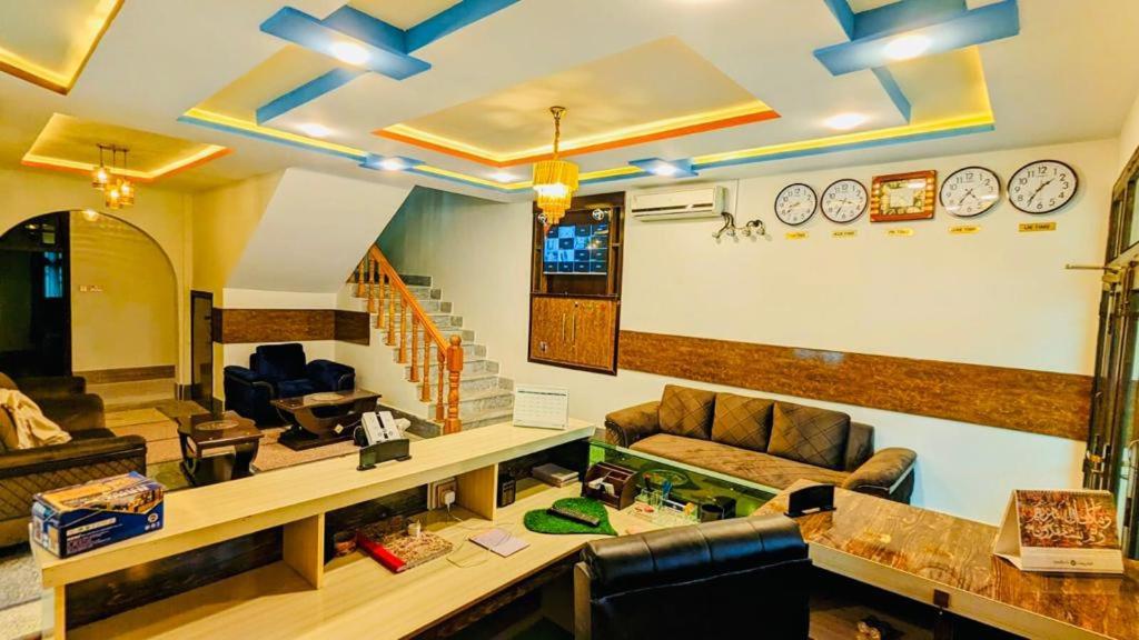 uma sala de estar com sofás e relógios na parede em Relax hotel em Kalām