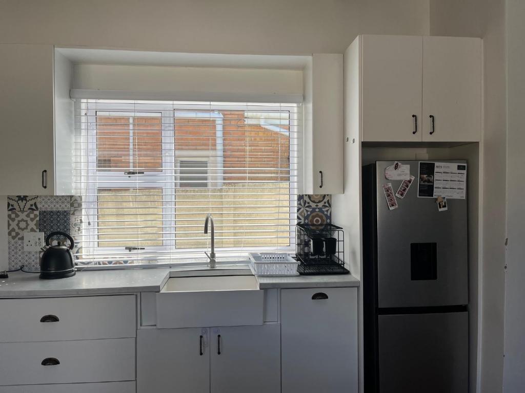 a kitchen with a sink and a window and a refrigerator at Kidds Beach Cottage in Kiddʼs Beach