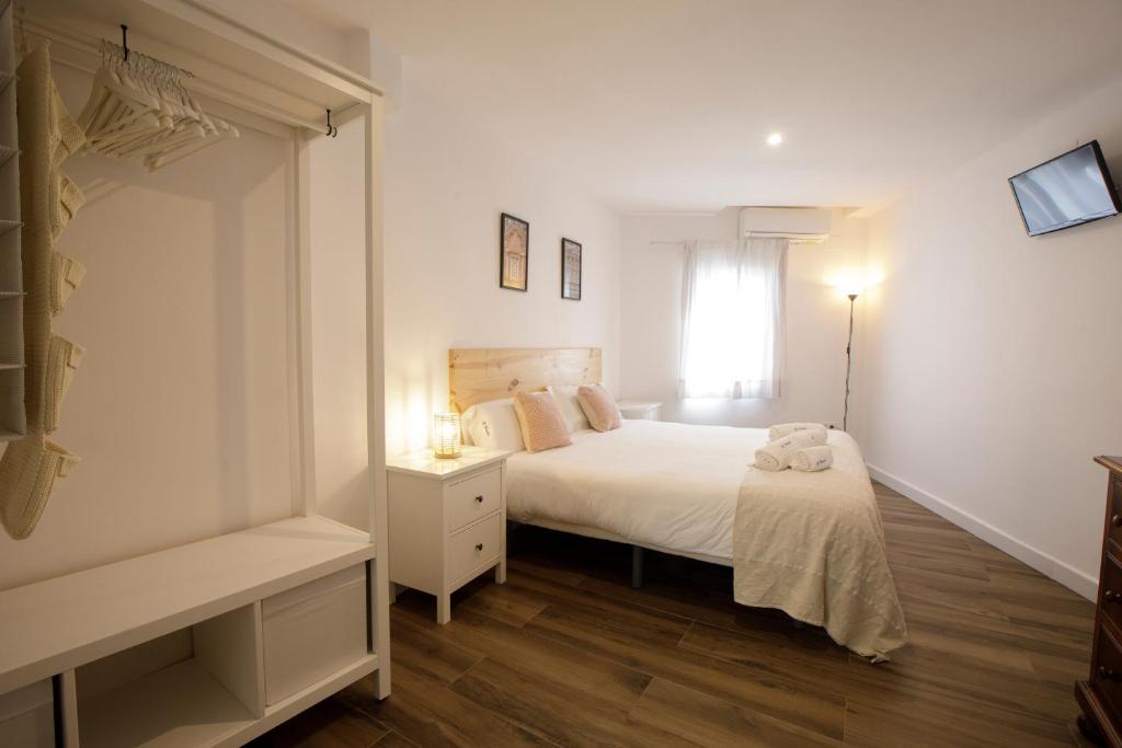 Apartamentos El balcón de la Trinidad Córdoba في قرطبة: غرفة نوم بيضاء بها سرير ونافذة
