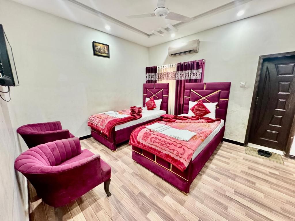 a bedroom with two beds and a chair at Al Atif Guest House in Islamabad