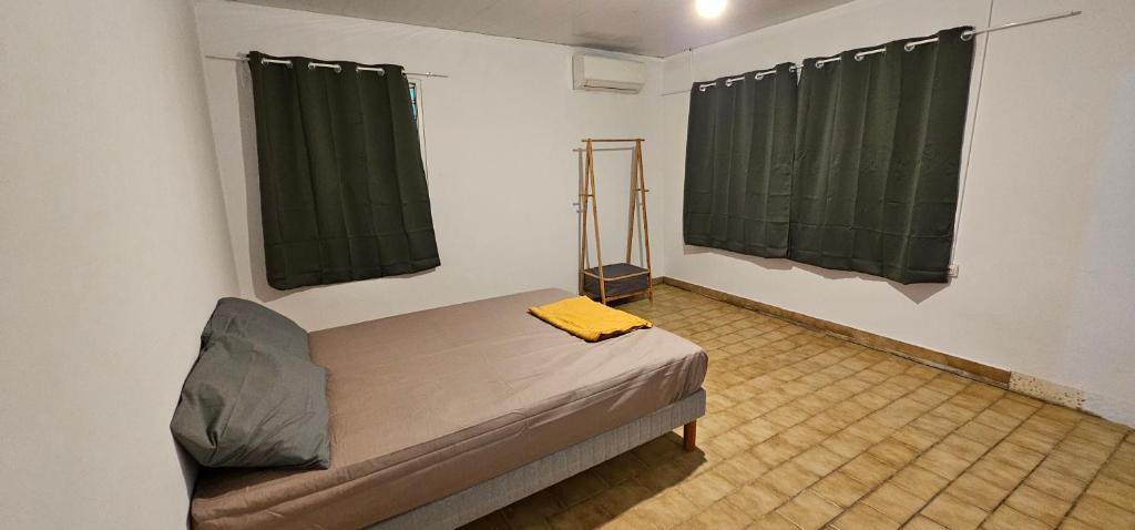 Habitación con 1 cama y 2 cortinas verdes en JUNGLE HOUSE, en Saint-Laurent-du-Maroni