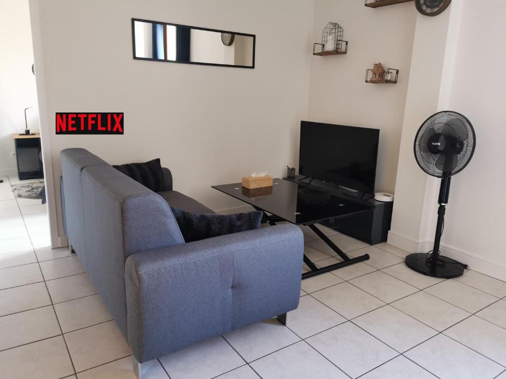 un salon avec un canapé bleu et une télévision dans l'établissement Charmant appartement à 1 minute du lac, à Annecy