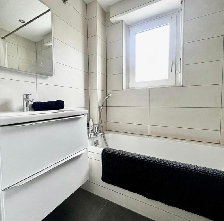 La salle de bains est pourvue d'une baignoire, d'un lavabo et d'une fenêtre. dans l'établissement Appartement Illzach, 5 personnes, à Illzach