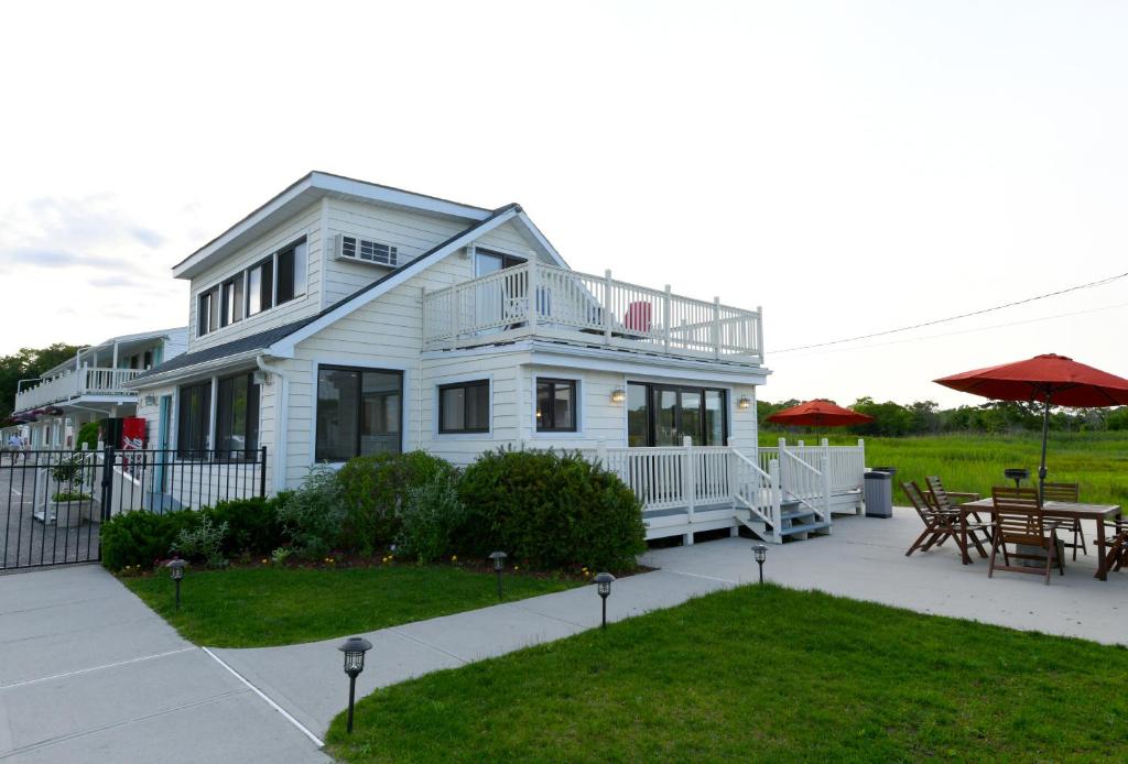 a white house with a deck and a patio at Bayview Resort in Hampton Bays