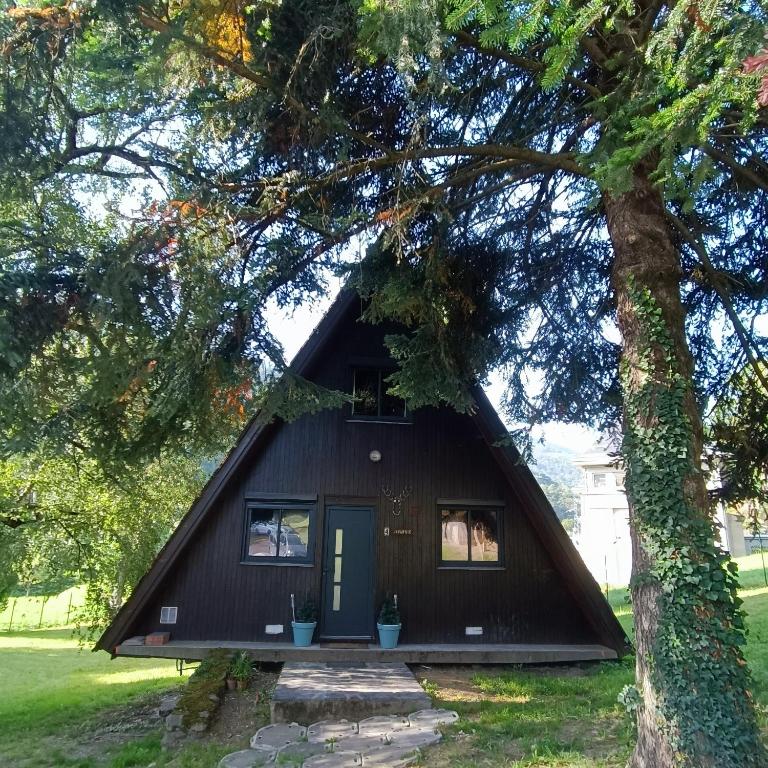 une petite maison noire avec un arbre dans l'établissement CHALET- Vallée de LUCHON - Vallée DE LA PIQUE, à Cierp