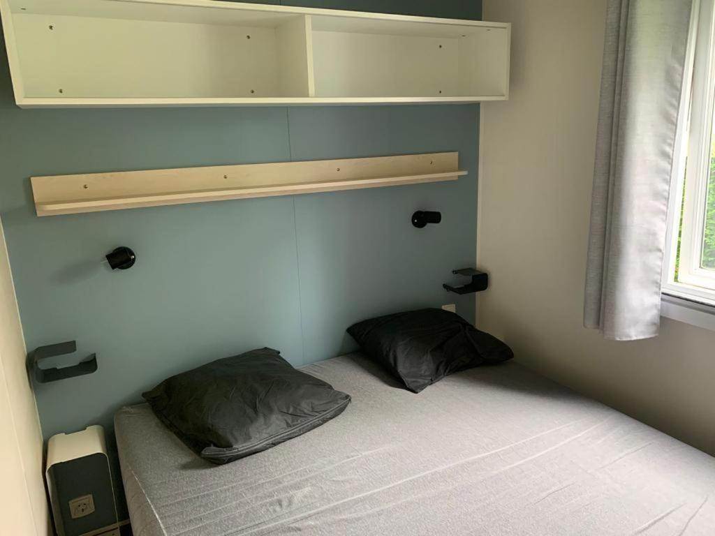 a small room with a bed with two pillows at Mobil-home Ouistreham in Ouistreham