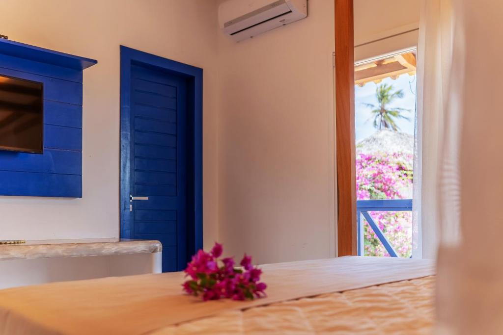 a room with a blue door and flowers on a table at Vila Gallina Pousada in Jericoacoara