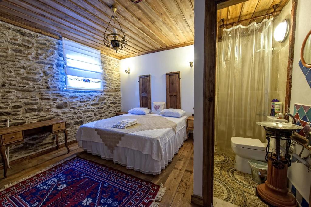 ein Schlafzimmer mit einem Bett und ein Badezimmer mit einer Badewanne in der Unterkunft Birgi Hotel Saliha Hanim Tas Konak in Birgi