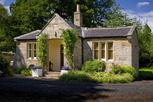 a small stone house with ivy on the front of it at Castle Lodge Haughton Castle in Hexham