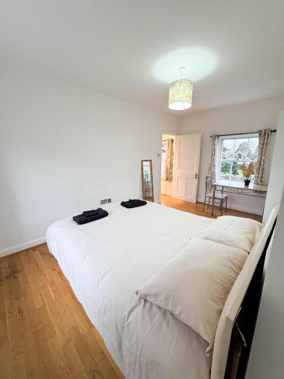 a bedroom with a large white bed with two black shoes on it at LA CASITA in Colindale