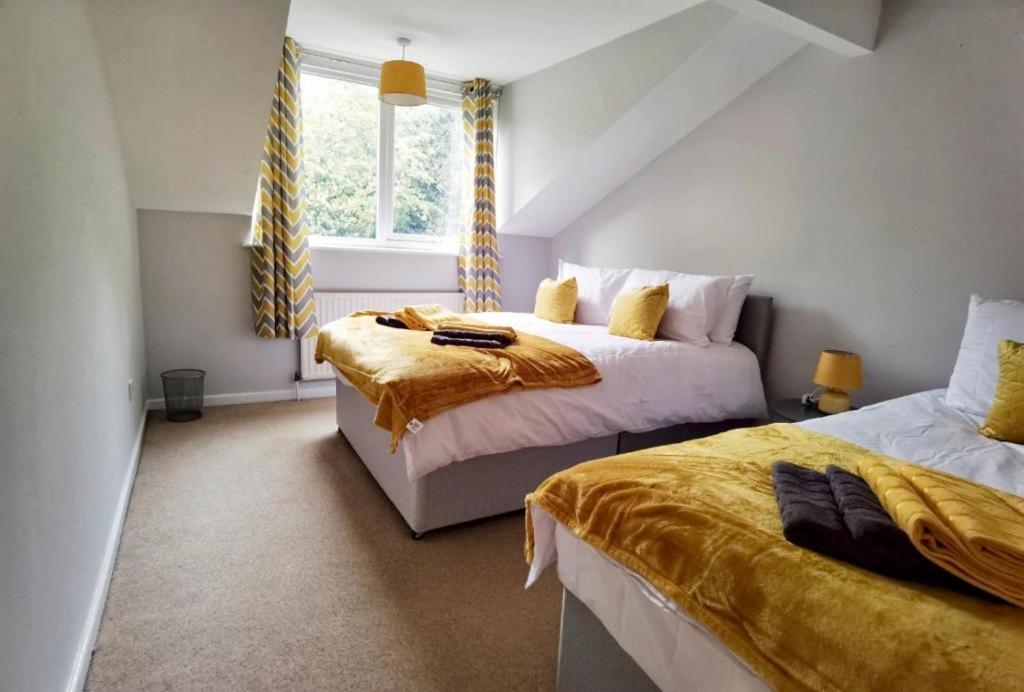 a bedroom with two beds and a window at Huge House, J26 M1, Sleeps 12 in Watnall Chaworth