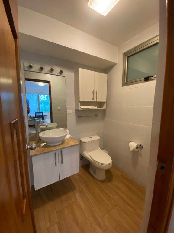 a bathroom with a white toilet and a sink at Apartamentos La Cañada in Guatemala