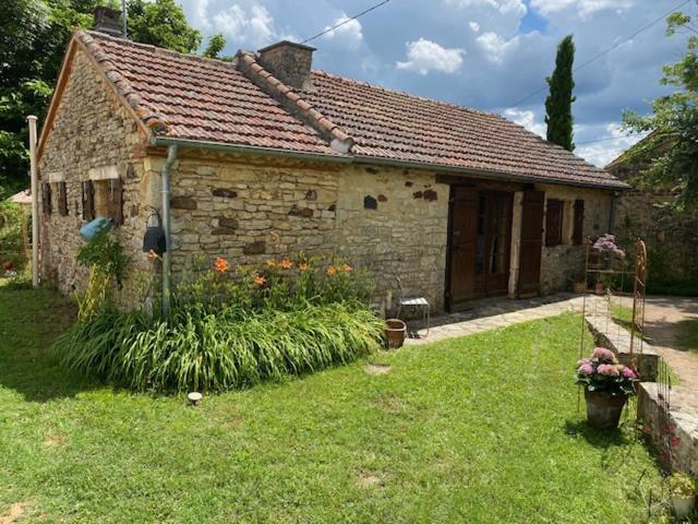 a small stone house with flowers in the yard at A l'Orée des Vignes in Sauveterre-la-Lémance