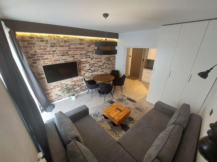 uma sala de estar com um sofá e uma parede de tijolos em Apartament nad Wisłą, bezpłatny parking em Cracóvia