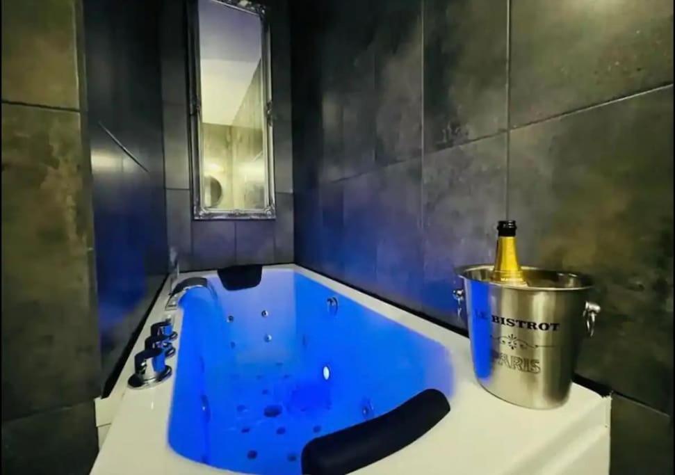 a bathroom with a tub with a bottle in a bucket at Orphelin studio avec Balnéo proche centre ville in Reims